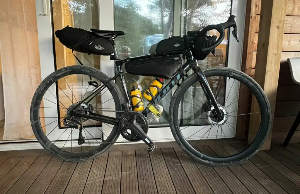 Bicicletta da gravel equipaggiata con borse da bikepacking, parcheggiata su una terrazza in legno.