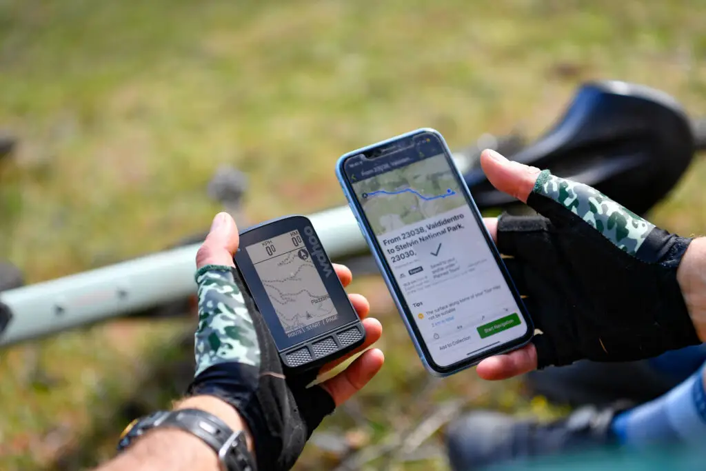 Ciclista che utilizza un navigatore GPS e uno smartphone per pianificare un percorso durante un viaggio di bikepacking.